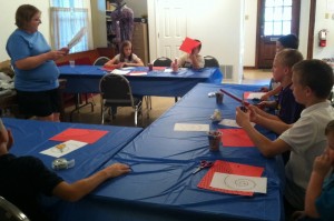 Each night students made their own reminder of the day’s main Bible story. Craft time was led by Angela Sampson with the help of George A. Heil. Here, on the first night, Angela explains to the children how to make the paper Tower of Babel. The crafts were done from scratch, with supplies donated by the congregation.