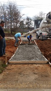 Workers pull the concrete for the new sidewalk up the ramp from the Office Area to the Florey Street parking. Photo: J.Galler.